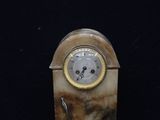 a marble clock that is on display on a black surface