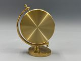 une image représentant un globe doré posé sur un socle, sur une surface blanche