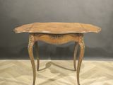 une vieille table en bois au plateau incurvé, posée sur un parquet
