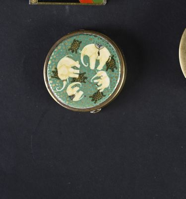 two small tins are sitting on a black surface with a picture of elephants on them