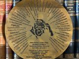 a close up of a plaque on a shelf in front of a row of books