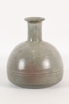 un vase gris posé sur une surface blanche