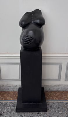 une sculpture noire représentant un ours assis sur un socle noir