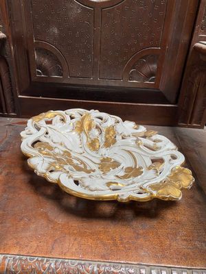 une assiette décorée, dorée et blanche, posée sur une table en bois