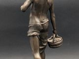 bronze statue of a boy with a basket of fruit on a rock