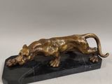 une statue en bronze représentant un lion, posée sur un socle en marbre