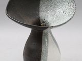 un vase noir et blanc posé sur une surface blanche