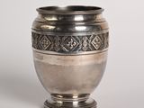 un vieux vase en argent posé sur une table blanche