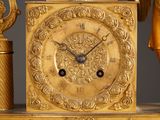 a gold clock sitting on top of a table next to a vase