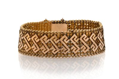 gros plan d'un bracelet en or sur une surface blanche