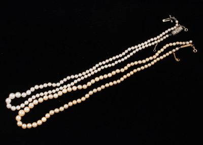 a close up of a necklace with pearls on a black background