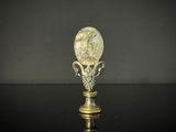 an antique brass spoon with a face on it on a black surface