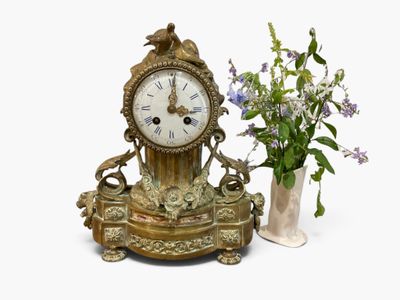 a clock and vase with flowers in it on a table