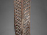 a wooden sculpture of a leaf on a pedestal on a gray background