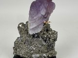 statue of a purple bird sitting on a rock on a white background
