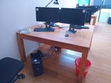two computer monitors sitting on a wooden desk in a room