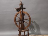 an old spinning wheel on a wooden stand on a wooden floor