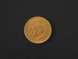 a close up of a gold coin on a black surface