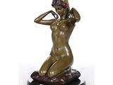 l'image d'une statue de bronze représentant une femme assise sur un rocher