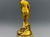 une statue en or représentant un homme debout sur un socle en marbre