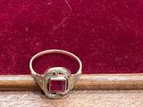 Gros plan sur une bague en or ornée d'une pierre rouge