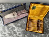 deux sets d'argenterie dans un coffret sur une table