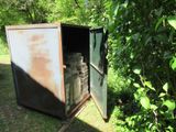 an old outhouse with a door open in the grass