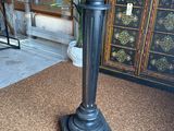 a black pedestal with a clock on it in the middle of a room