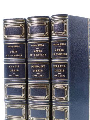 trois livres bleus sont alignés sur une surface blanche