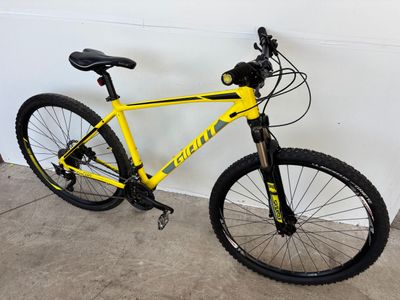 un vélo jaune garé dans un garage, près d'un mur blanc