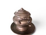 a small metal pot on a saucer on a plate