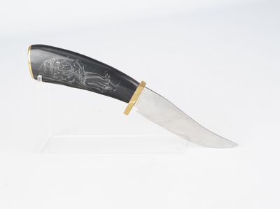 un couteau au manche noir posé sur un socle transparent