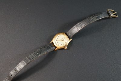 une image représentant une montre-bracelet posée sur une table, sur fond noir