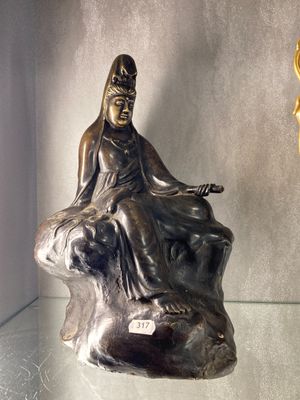 une statue représentant une femme assise sur un rocher à côté d'une horloge