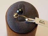 une bague sertie d'une perle noire, posée sur un coffret en bois