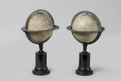 une paire de globes sur des socles, sur fond gris