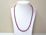 collier de perles violettes sur un mannequin à socle blanc