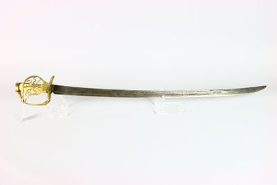 une vieille épée à la poignée dorée posée sur une surface blanche