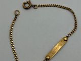 a close up of a gold bracelet with a tag on it