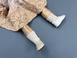 an old fashioned doll laying on a table with a pair of shoes