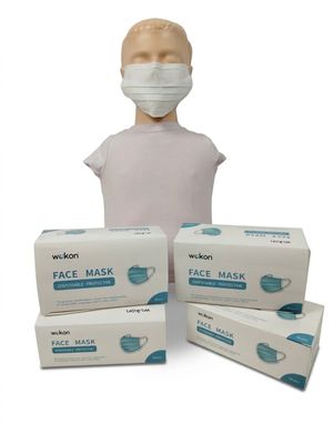une personne portant un masque à côté de trois boîtes de masques jetables
