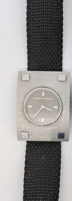 une montre argentée avec un bracelet noir posée sur une surface blanche
