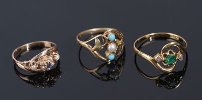 three gold rings with green and white stones on a black surface