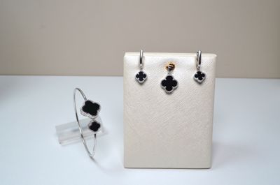 silver and black flower earrings and ring on a white display case