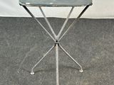 une petite table en métal avec un plateau vert, posée sur un tapis