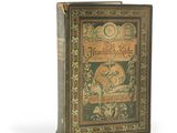 an old book sitting on top of a white table next to a clock