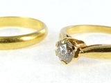 two gold wedding rings with a diamond on top of them