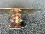 un bol en verre avec un socle doré posé sur une table