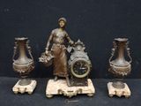 trois vases en bronze et une horloge posés sur une table
