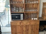 a wooden cabinet with a microwave on top of it